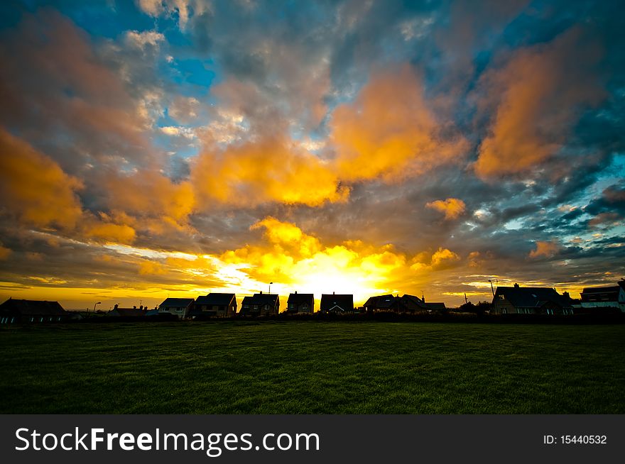 Colourful sunset with houses and field