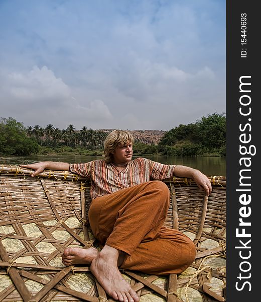 Caucasian man in Indian traditional clothes sailing in round boat-basket. Caucasian man in Indian traditional clothes sailing in round boat-basket