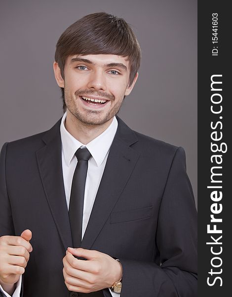 Portrait of young happy businessman over grey background