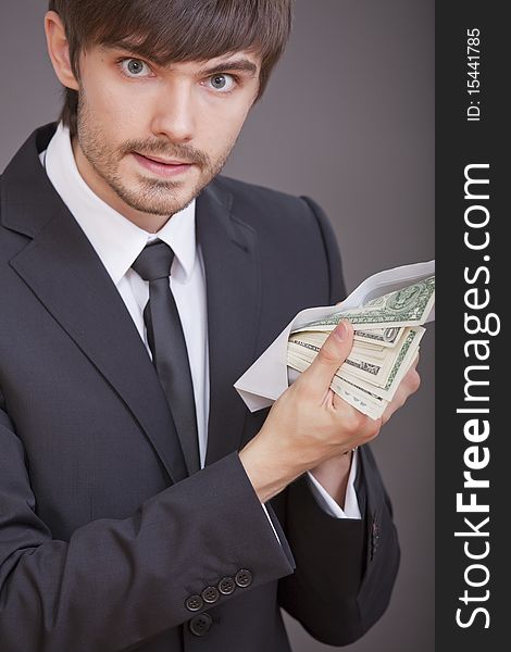 Young businessman holding many one dollars in envelope. Young businessman holding many one dollars in envelope