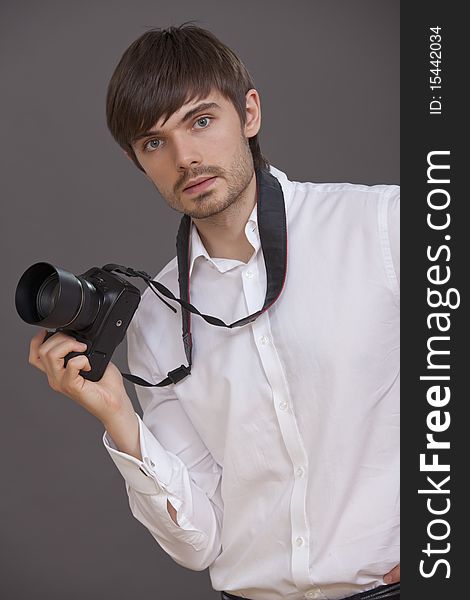 Male photographer in white shirt with photo camera on grey background. Male photographer in white shirt with photo camera on grey background