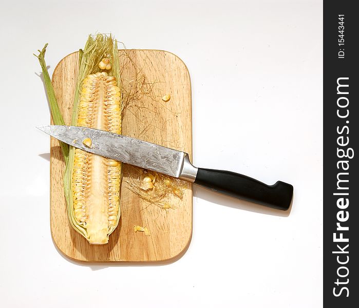 Still life with a natural corn cob with a knife and cutting board. In isolation