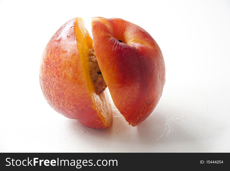 peach cut in the middle half with nut exposed. peach cut in the middle half with nut exposed