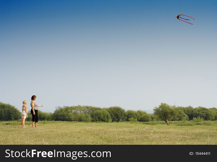 The grand daughter and the grandmother start a kite on a meadow