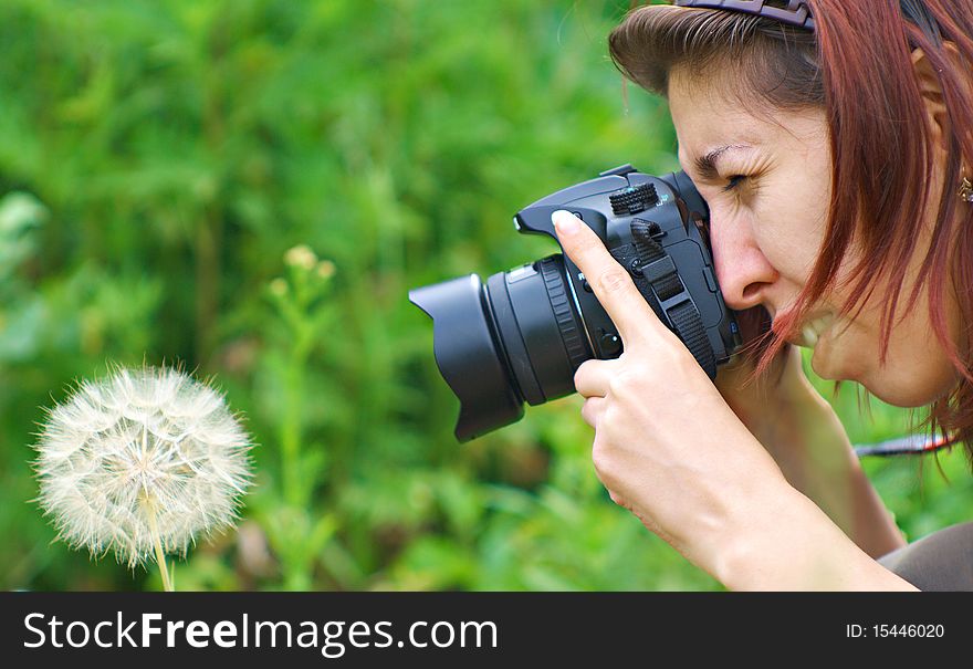 Girl-photographer involved in photographing nature. Before her large dandelion.