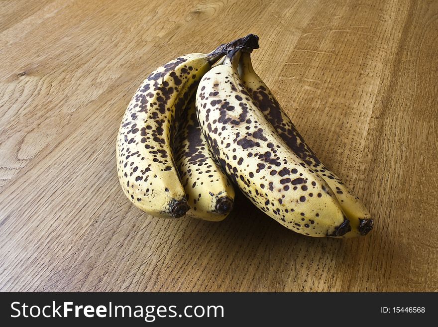 Ripe spotty bananas on a wooden surface. Ripe spotty bananas on a wooden surface