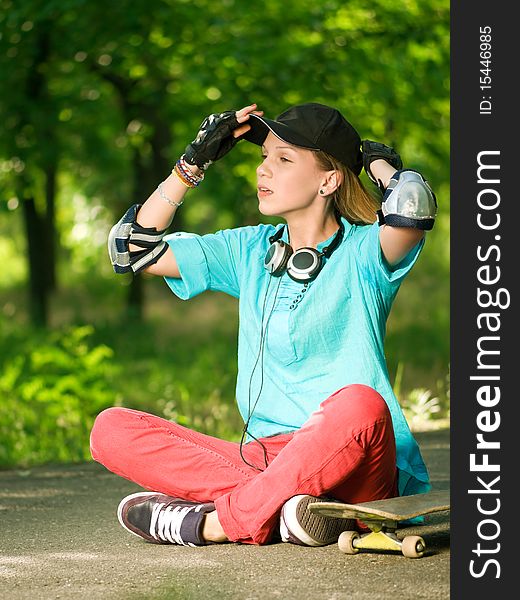 Beautiful teenage girl with skateboard in the green park