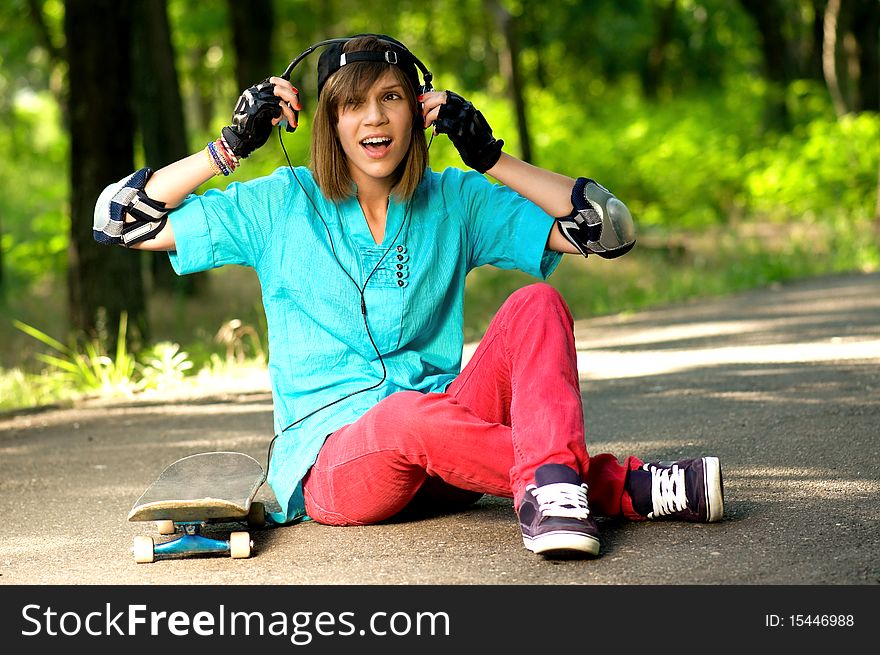 Beautiful teenage girl with skateboard in the green park
