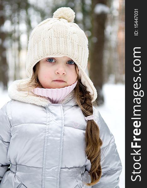 Toddler girl in warm white hat in winter forest with long plait. Toddler girl in warm white hat in winter forest with long plait