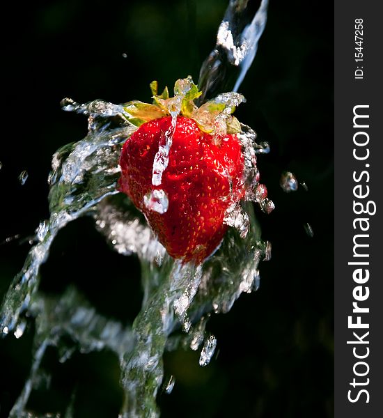 Strawberry in a stream of water on a dark background