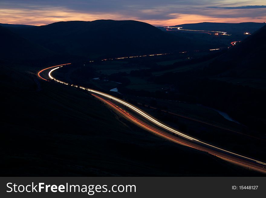 The blurred light of vehicles travelling on the M6 motorway through the mountains of the Lake District. The blurred light of vehicles travelling on the M6 motorway through the mountains of the Lake District.
