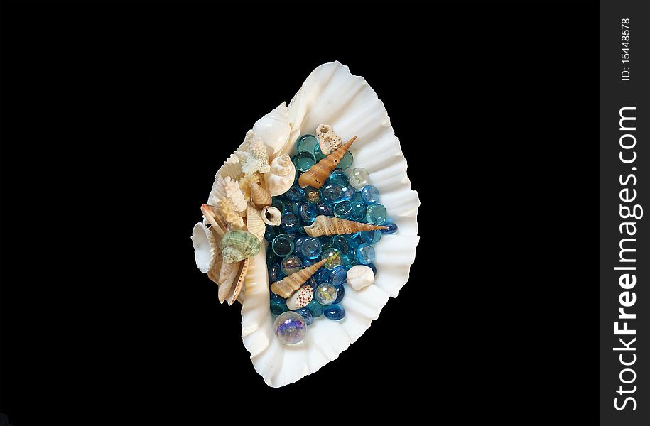 Large sea shell with blue glass stones and small shells, isolated on black