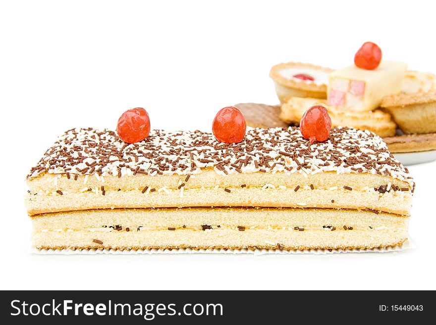 Mix of sweets with chocolate sponge cake, cookies and cupcakes. With red cherry on top. Isolated over white background.