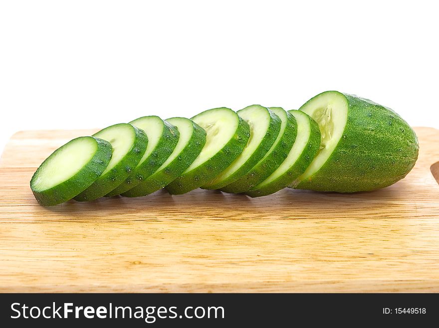 Green cucumber with slices on wooden plate