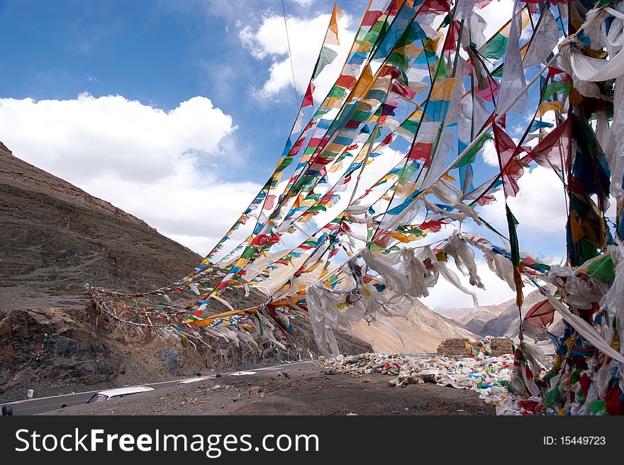 Mountain road with religious flags in various colors against blue sky. Mountain road with religious flags in various colors against blue sky