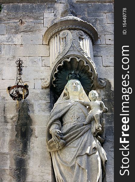 Medieval stone wall with a statue and a lantern on it. Medieval stone wall with a statue and a lantern on it