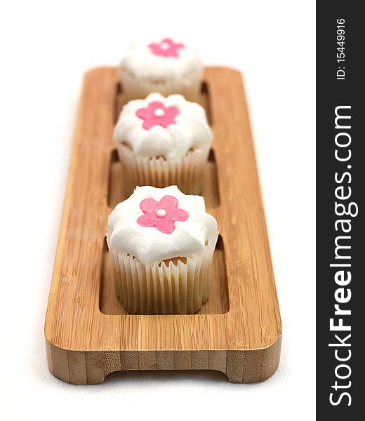 Freshly baked cup cakes with pink flowers and white frosting