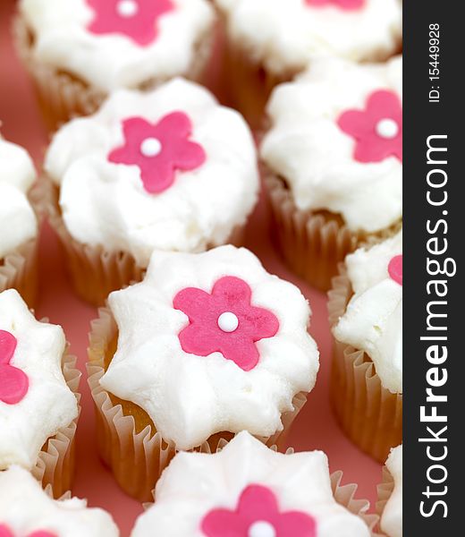 Freshly baked cup cakes with pink flowers and white frosting