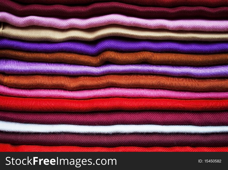 A collection of stacked fabrics of different colors. A collection of stacked fabrics of different colors