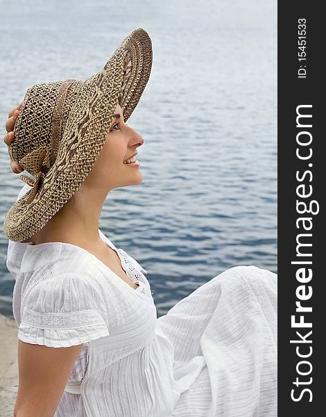 Happy young girl in the bonnet near the sea