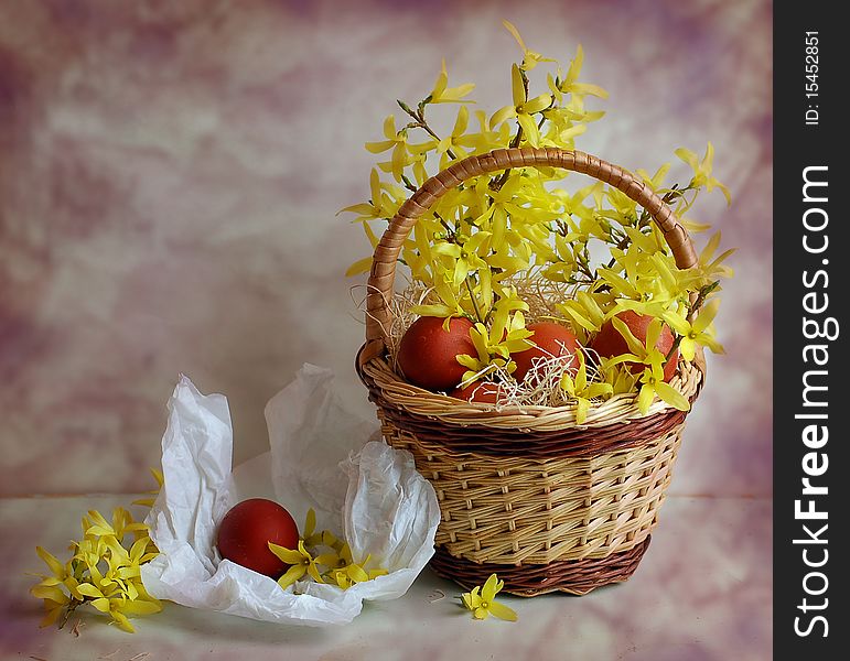 The dyed eggs and yellow flowers lie in a small basket. The dyed eggs and yellow flowers lie in a small basket