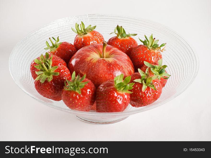 Strawberries and apple in a glass bowl