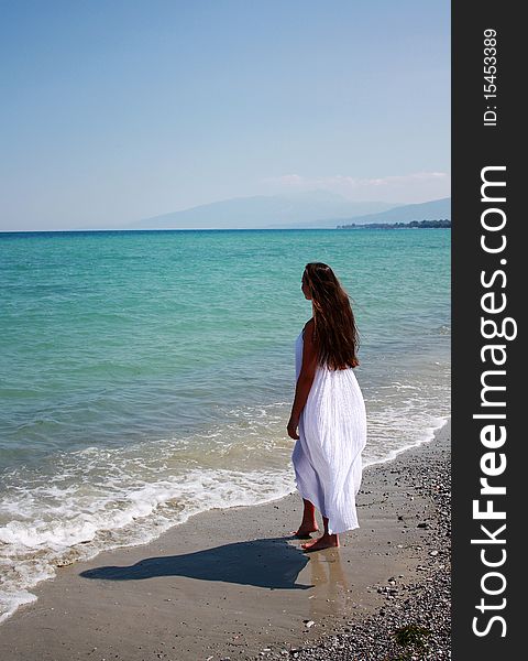 Beautiful woman in white long dress relax on the beach. Greece. Aegean Sea