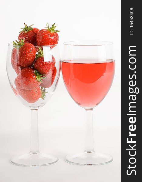 A vertical image of two wine glasses one with wine and the other filled with fresh strawberries. A vertical image of two wine glasses one with wine and the other filled with fresh strawberries