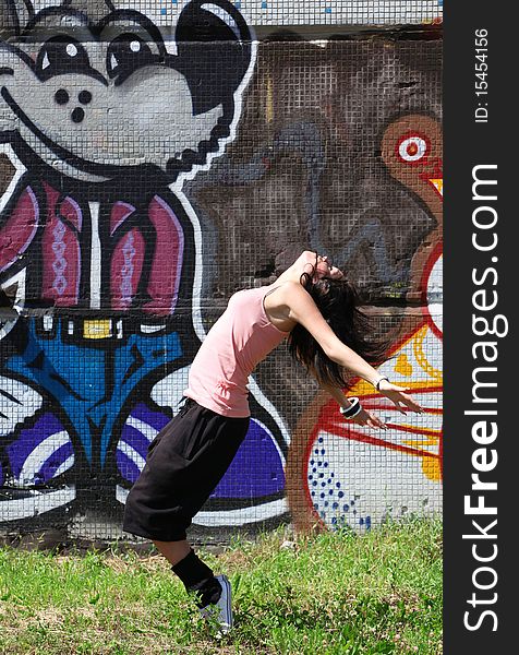 Woman modern dancer in city against graffiti wall