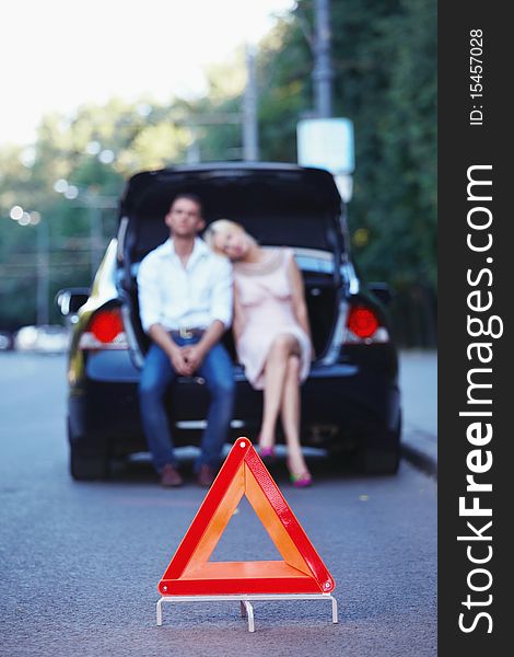 Young couple in a car with a red triangle in the foreground. Young couple in a car with a red triangle in the foreground