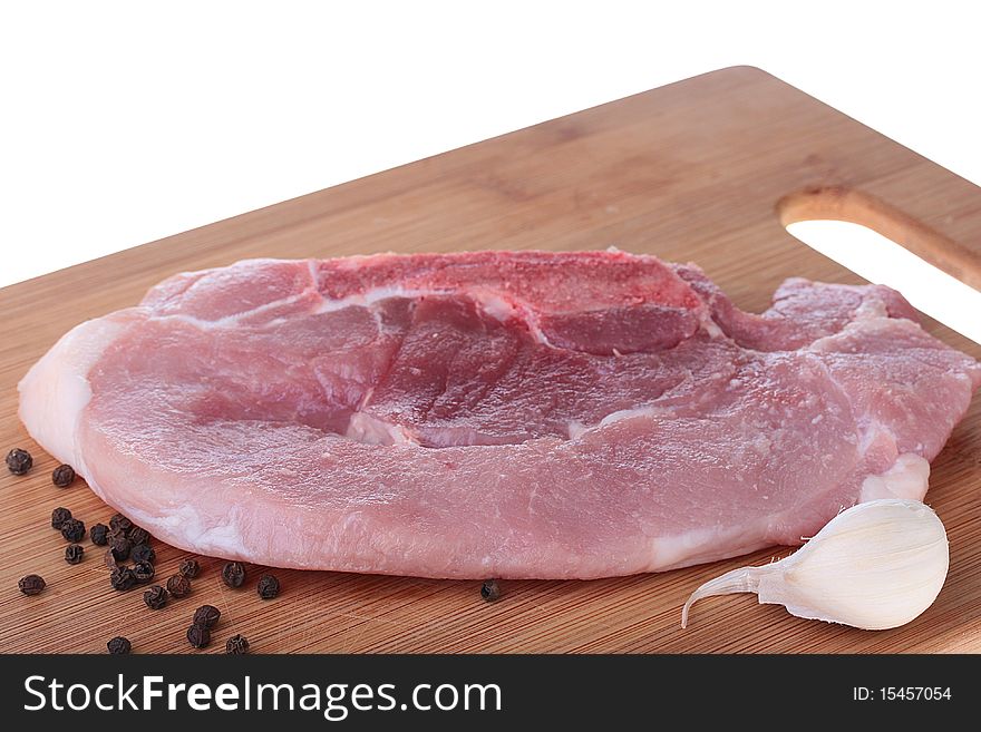 Piece of crude meat with black pepper on a kitchen board. Piece of crude meat with black pepper on a kitchen board.