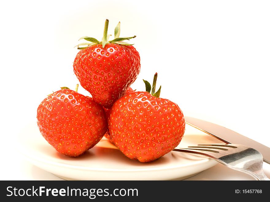 Four strawberries on the plate with fork and knife on the right. Four strawberries on the plate with fork and knife on the right