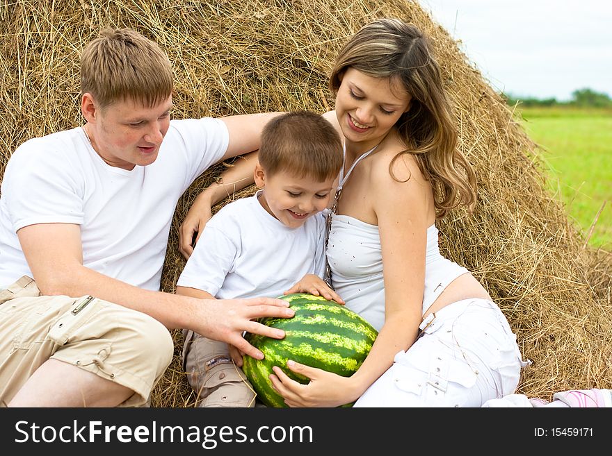 Happy family in haystack or hayrick with watermelon. Happy family in haystack or hayrick with watermelon