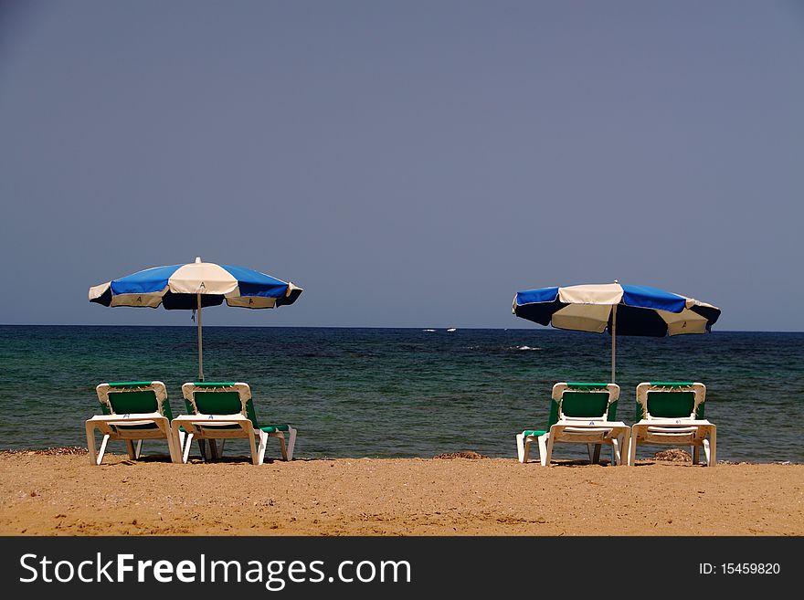 Two pairs of beach beds with open parasols