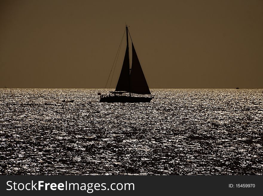 Black silhouette of the sailboat against the eveing sun on the sea. Black silhouette of the sailboat against the eveing sun on the sea