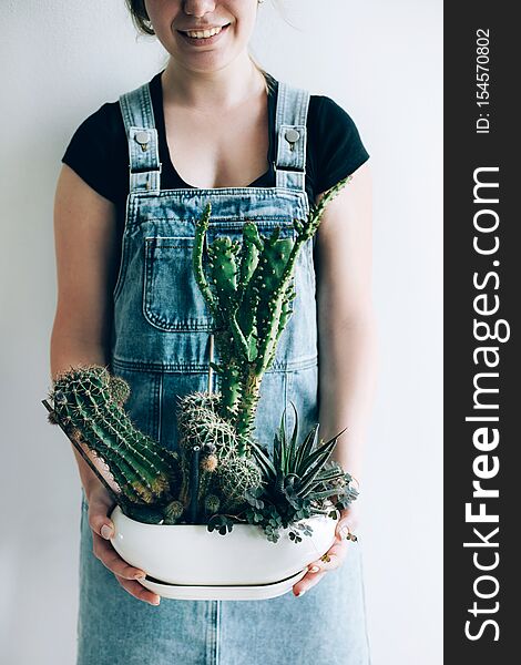 A pot with big cactus is in the woman`s hands.