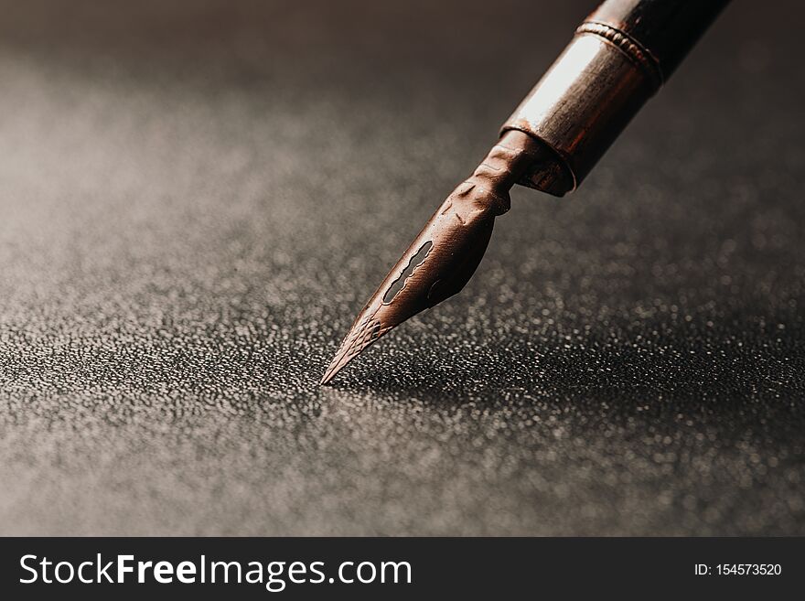 Old fountain pen on a black textured background. Old fountain pen on a black textured background