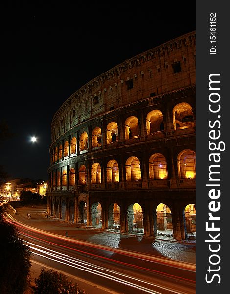 Roman Colosseum at night with moon and car trail light. Roman Colosseum at night with moon and car trail light