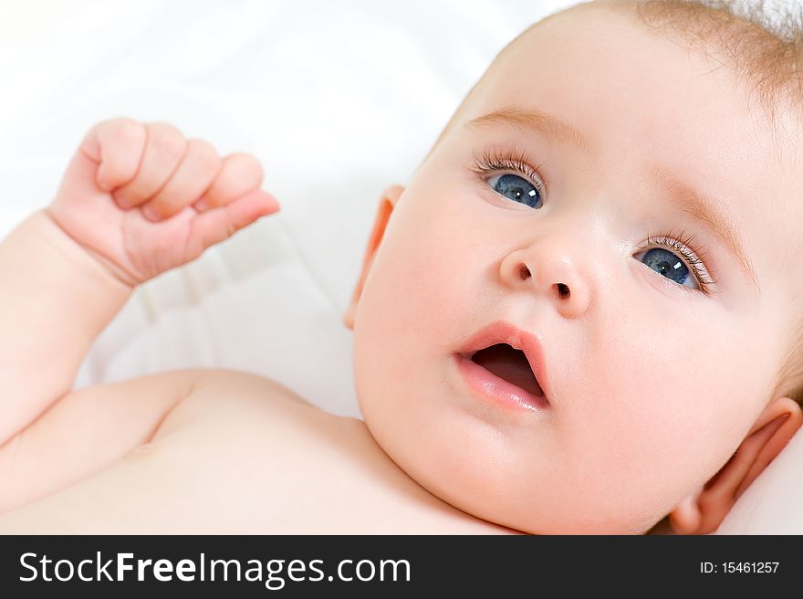 Closeup smiling face of a beautiful newborn girl lying on pillow