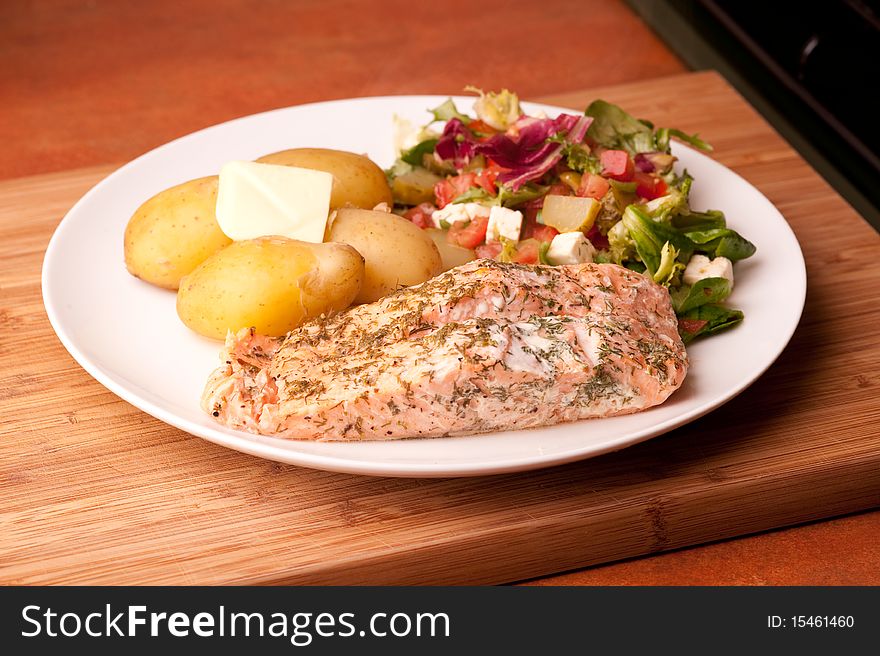 Salmon on a plate with potatoes and salad