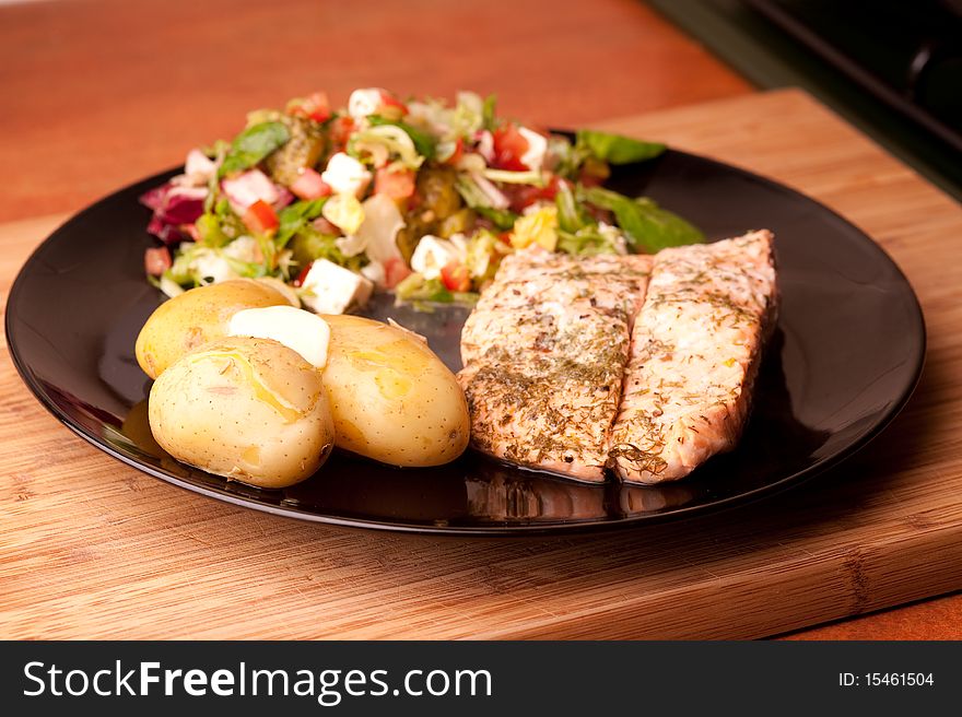 Salmon on a plate with potatoes and salad