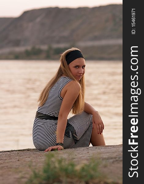 Pretty young girl sitting at the seaside