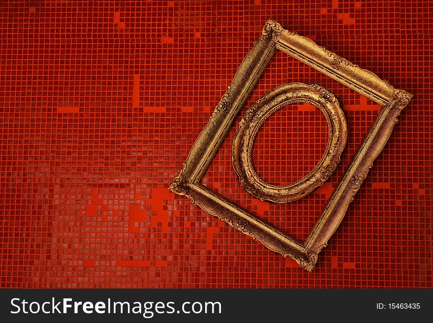 Old frames hanged on a wall covered in red tiles.
