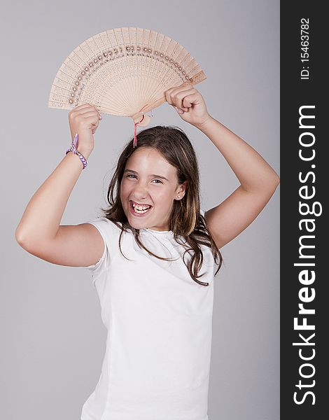 Young girl playing with a fan and smiling. Young girl playing with a fan and smiling