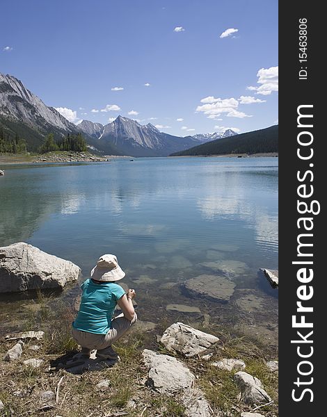 Woman sitting in front of a lake admiring the Canadian Rocky Mountains. Woman sitting in front of a lake admiring the Canadian Rocky Mountains