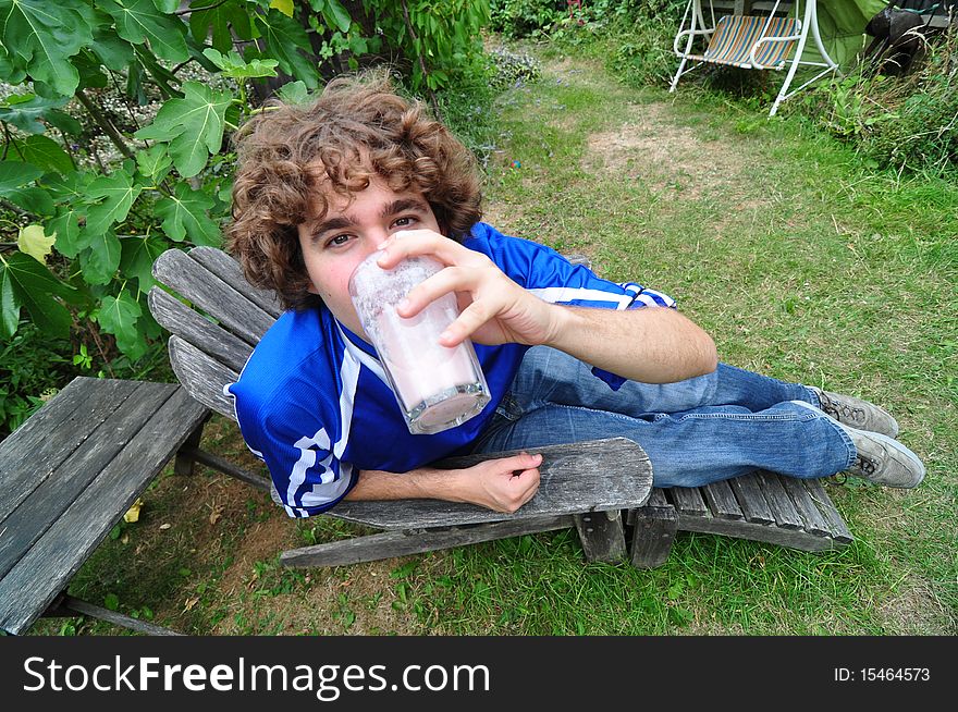 Disheveled boy drinking a glass of milkshake in garden. Disheveled boy drinking a glass of milkshake in garden