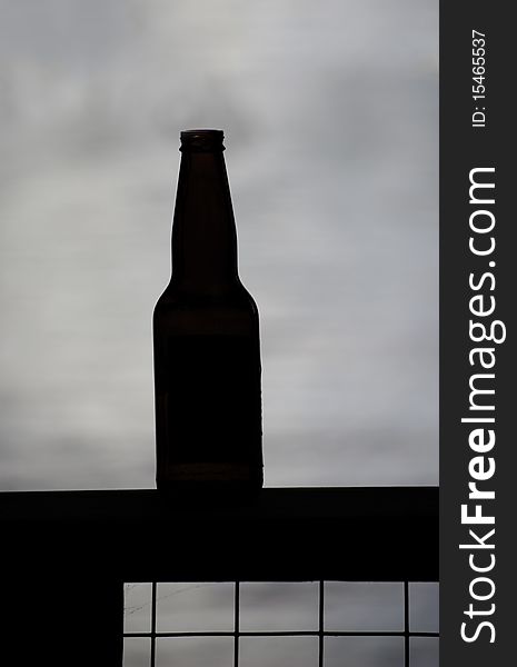 An empty beer bottle silhouetted on a lake. An empty beer bottle silhouetted on a lake