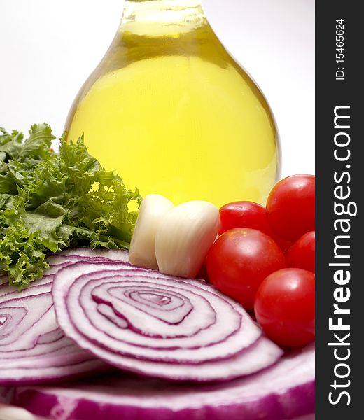 Salad ingredients on white background, tomatoes, garlic, red onions, greens and olive oil decanter. Salad ingredients on white background, tomatoes, garlic, red onions, greens and olive oil decanter