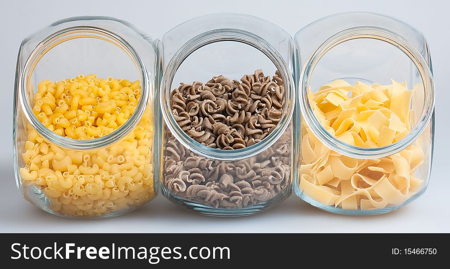 Pasta in glass jars on white background