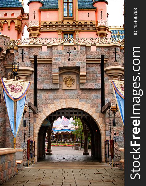 Looking through a fantasy castle's draw bridge entrance to see a carousel in the distance. Looking through a fantasy castle's draw bridge entrance to see a carousel in the distance